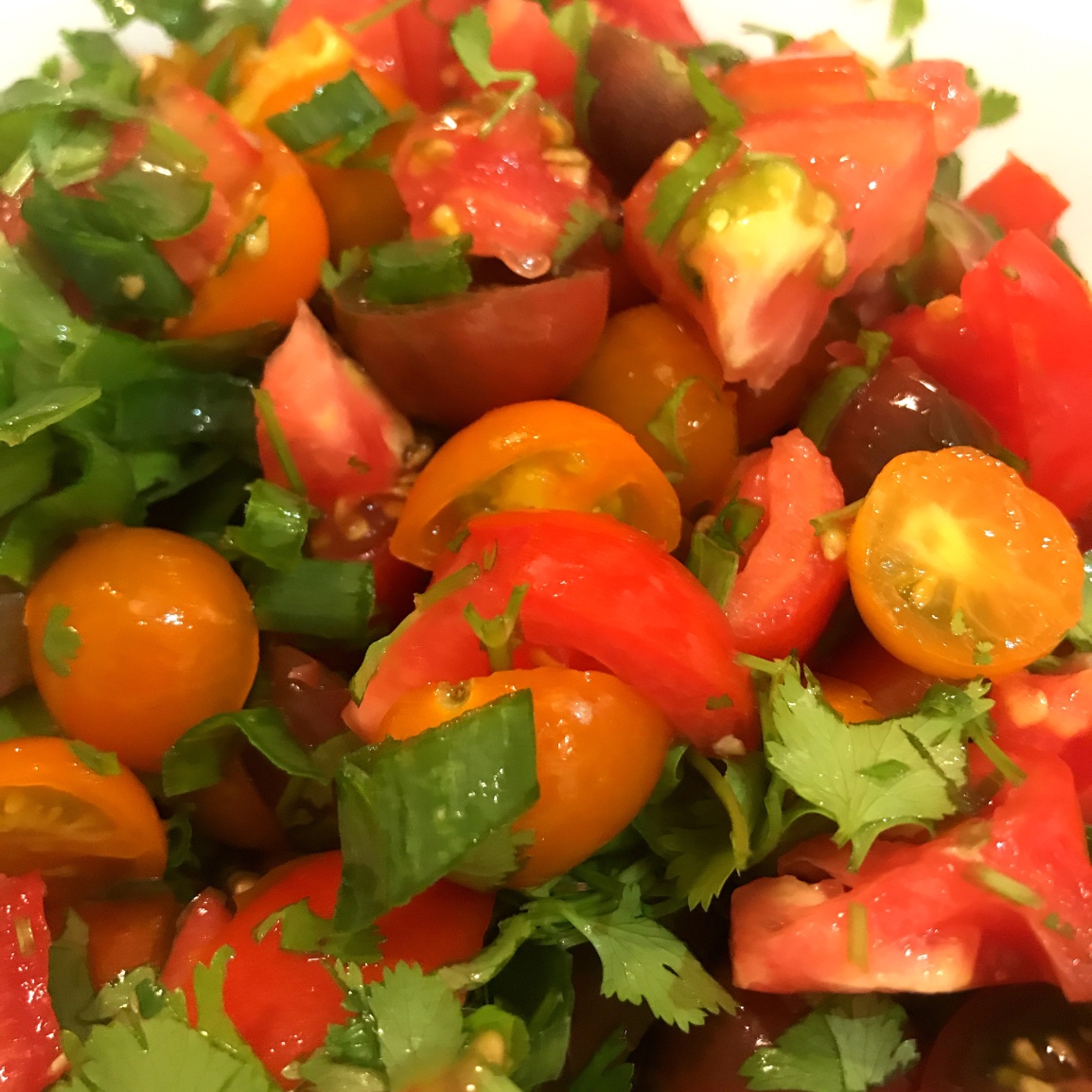 A closeup of pico di gallo, a fresh raw tomato and herb dish